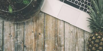 Laptop, pineapple and flower on a wooden desk. Illustrative